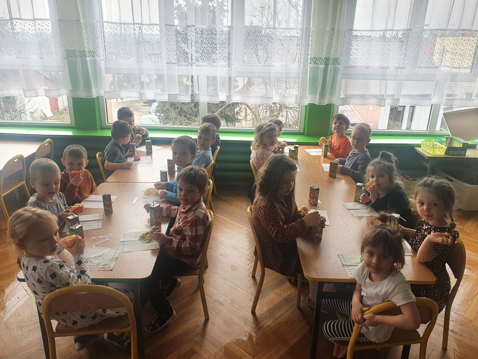 Grupa dzieci je poczęstunek przy stolikach