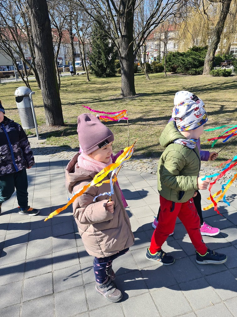 Chłopcy maszerują alejkami parku miejskiego z wiosennymi gaikami.