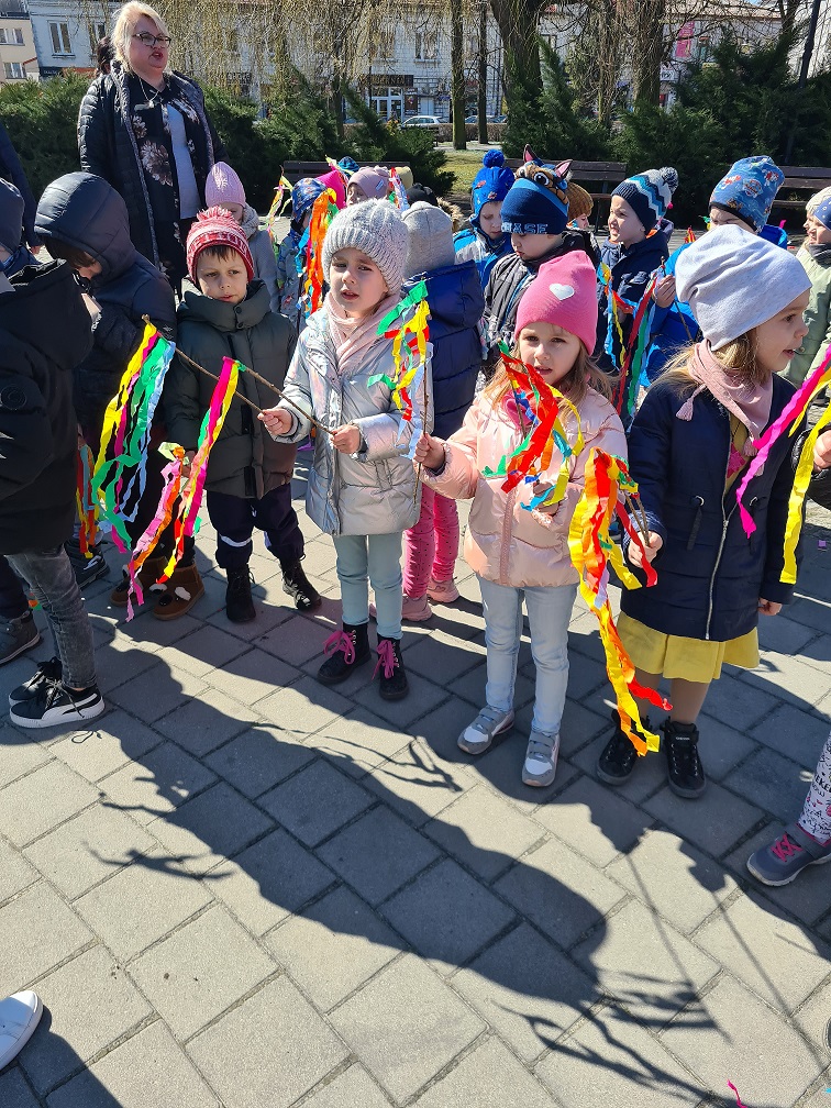 Dzieci w parku miejskim śpiewają piosenkę pt. "Marzanna - zimowa panna".