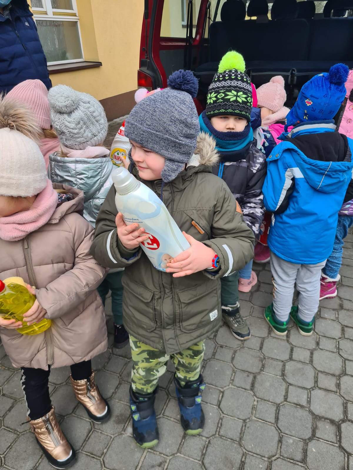Dzieci stoją przed przedszkolem z darami dla uchodźców z Ukrainy