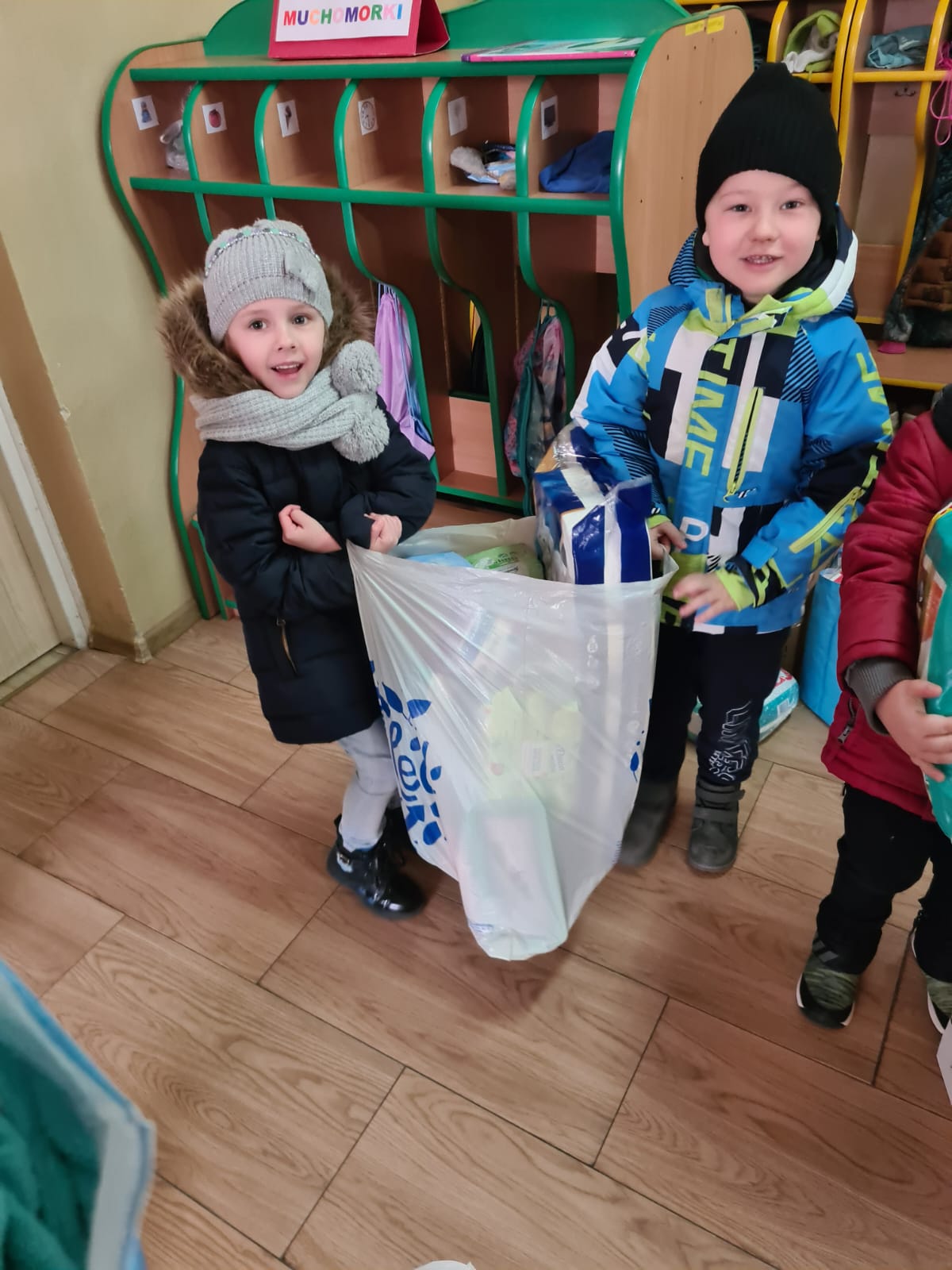 Chłopiec i dziewczynka trzymają w rękach dużą torbę z darami dla uchodźców z Ukrainy