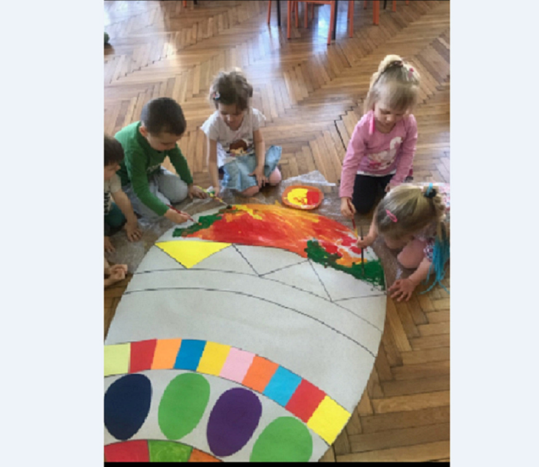 Dzieci malują pisankę za pomocą pędzli i farb plakatowych