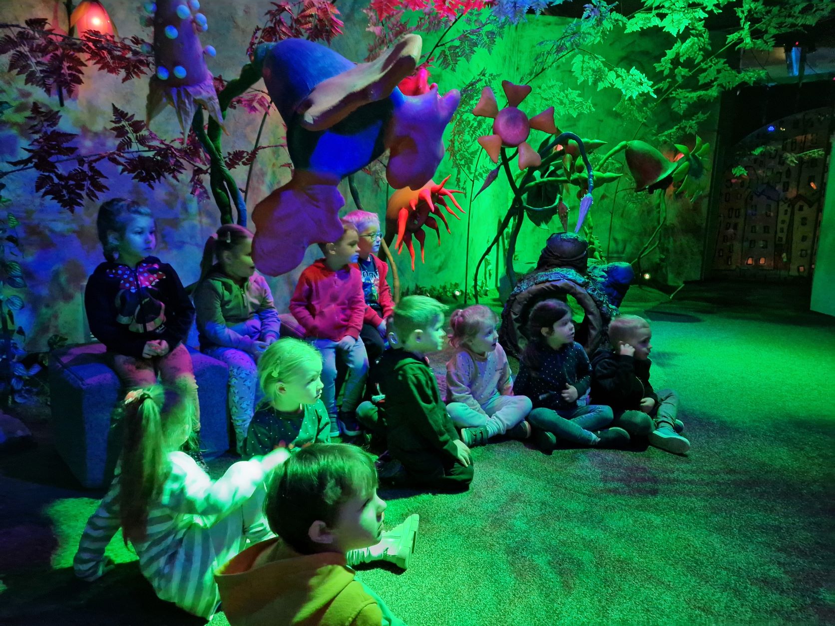 Dzieci siędzą na podłodze w " Czarodziejskim Ogrodzie"