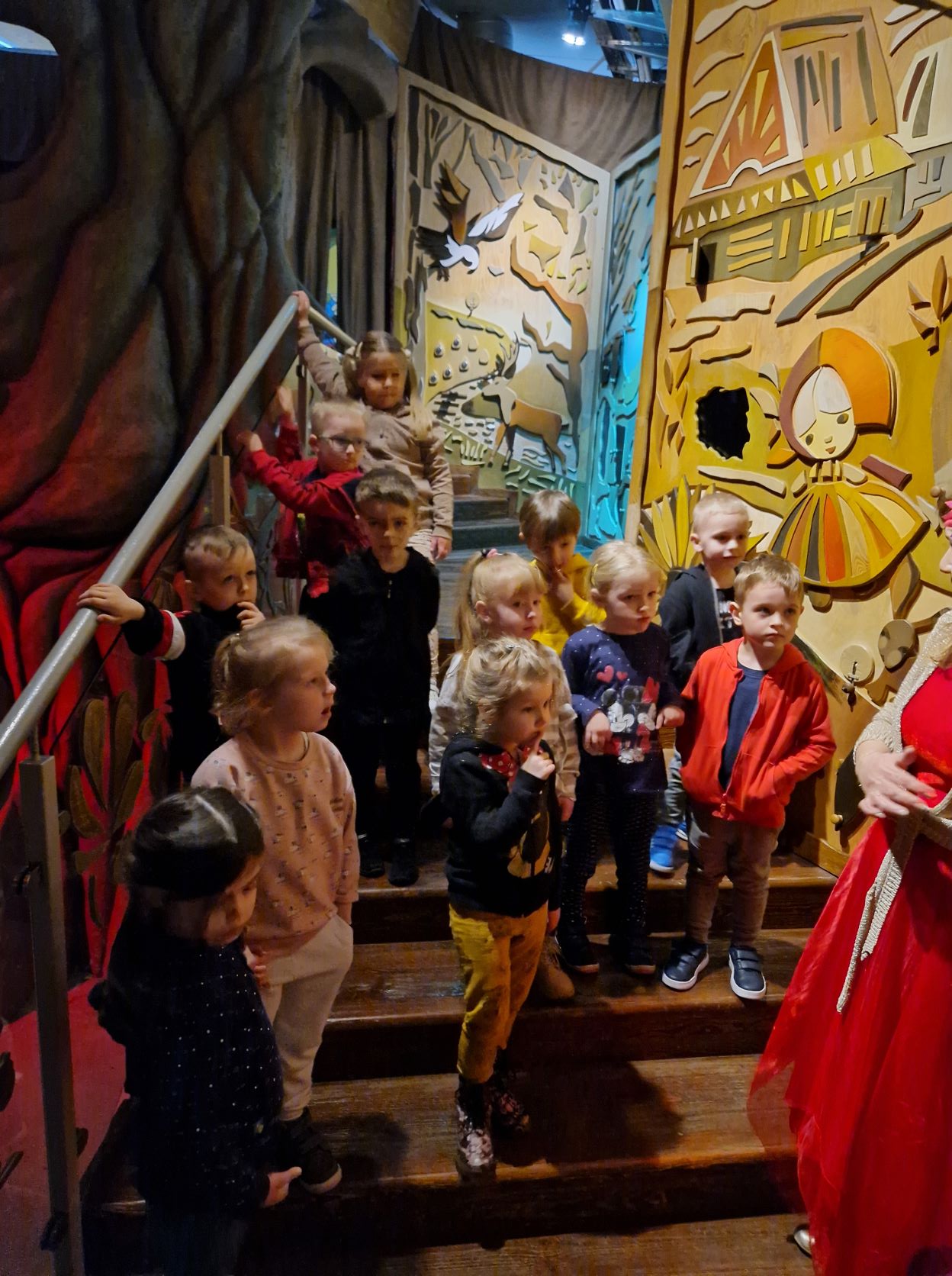 Dzieci stoją w Pałacowym Korytarzu, oglądają postaci księżniczek i książąt