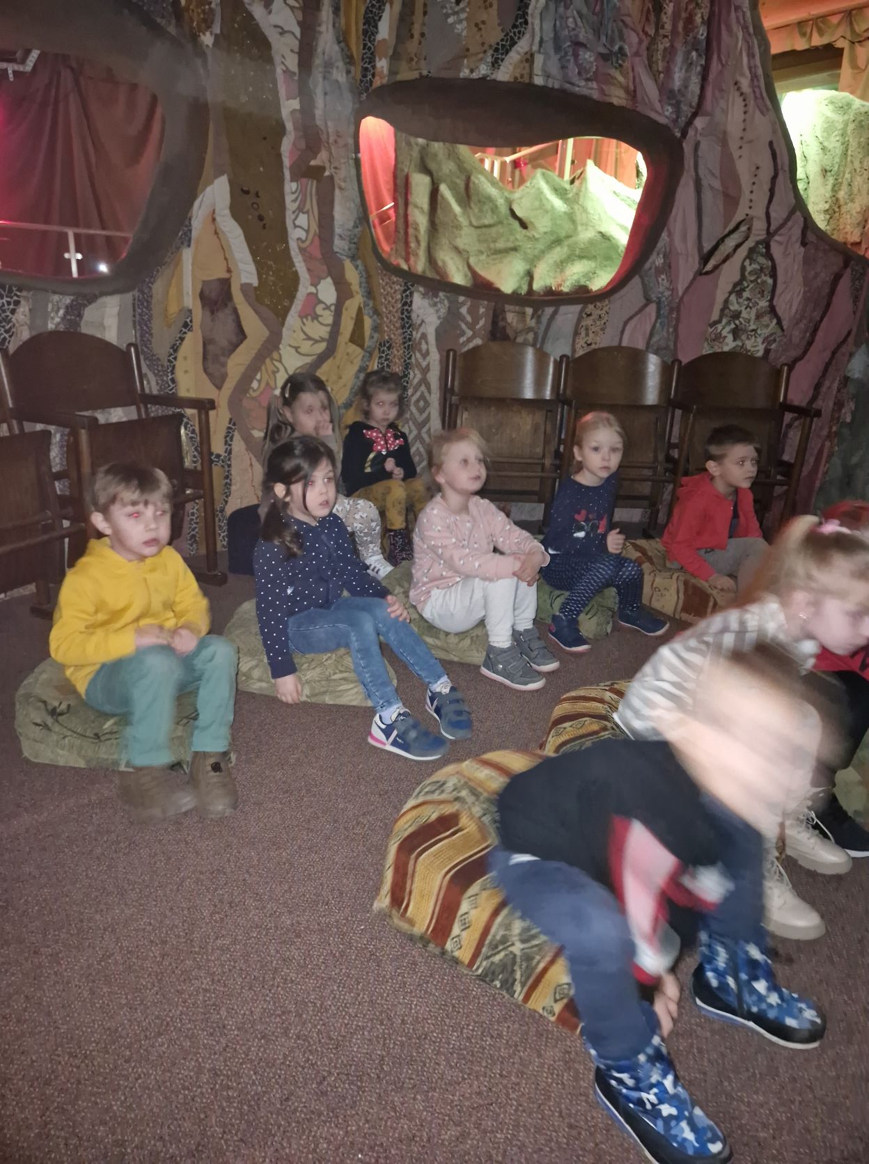 Dzieci siedzą na podłodze i oglądają bajkę o Koziołku Matołku