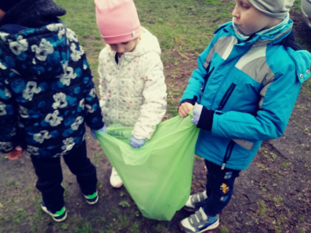 Dzieci zbierają śmieci wokół przedszkola