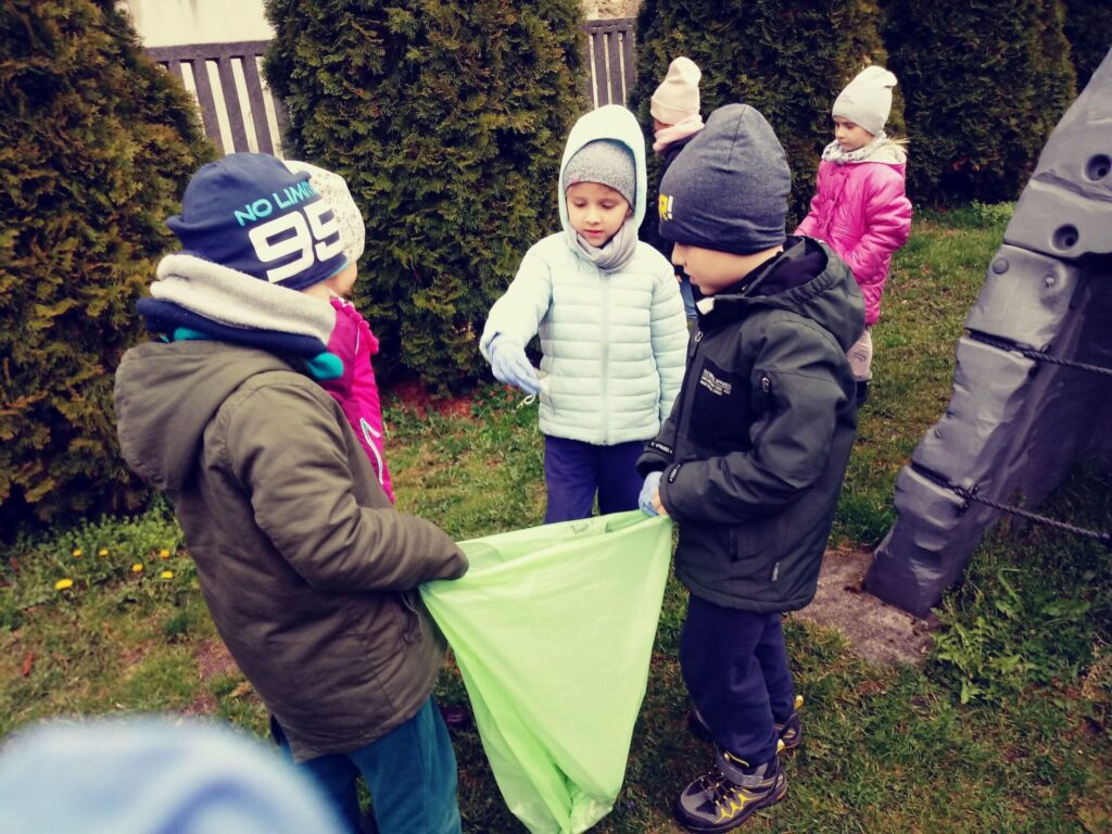 Dzieci zbierają śmieci wokół przedszkola