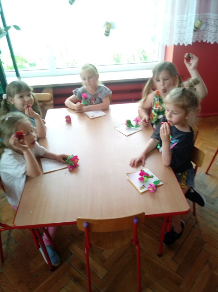 Dziewczynki przy stoliku jedzą truskawki