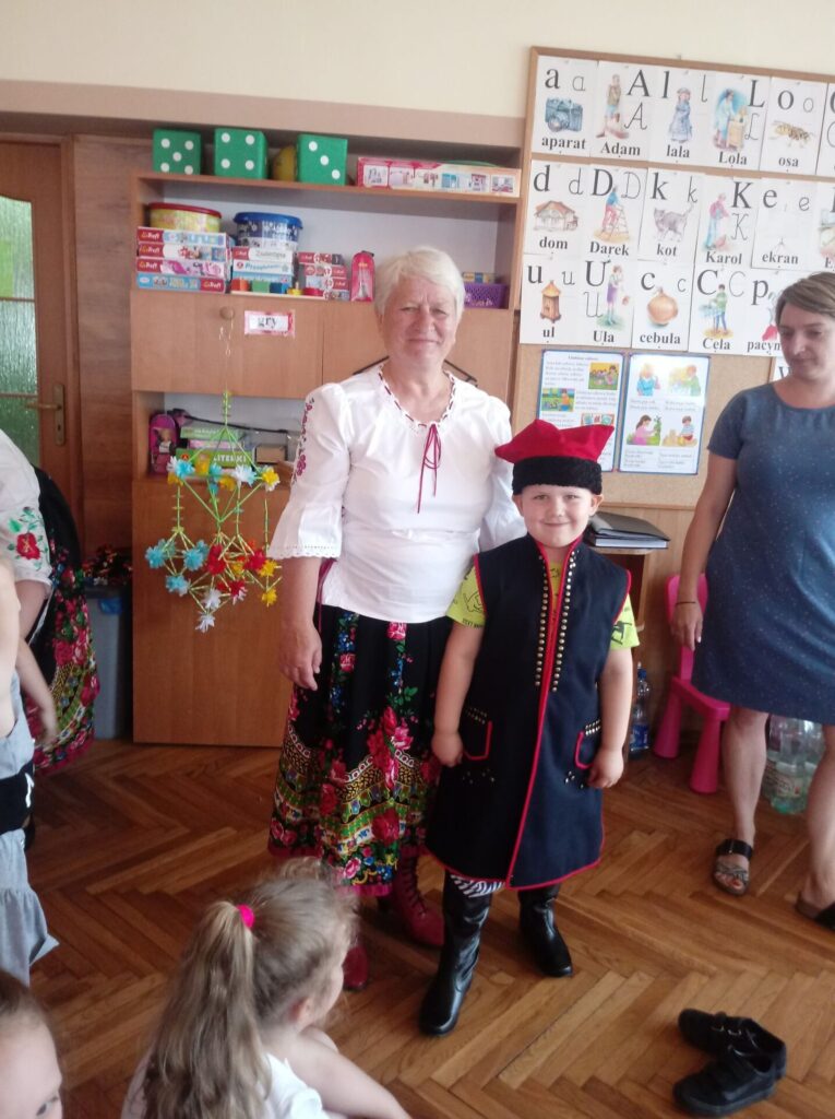 Chłopiec z panią z Koła Gospodyń Wiejskich prezentuje tradycyjny strój ludowy             