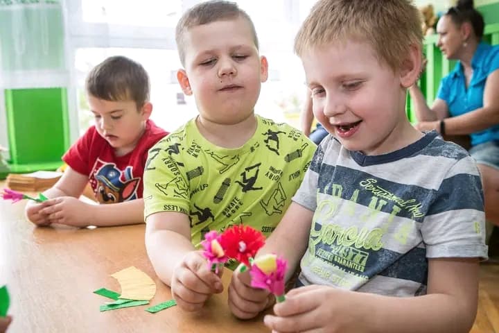 Dwaj chłopcy pokazują samodzielnie wykonane ludowe kwiatki