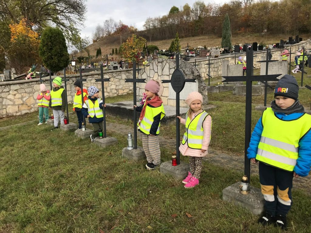 Dzieci stoją przy grobach żołnierzy. 