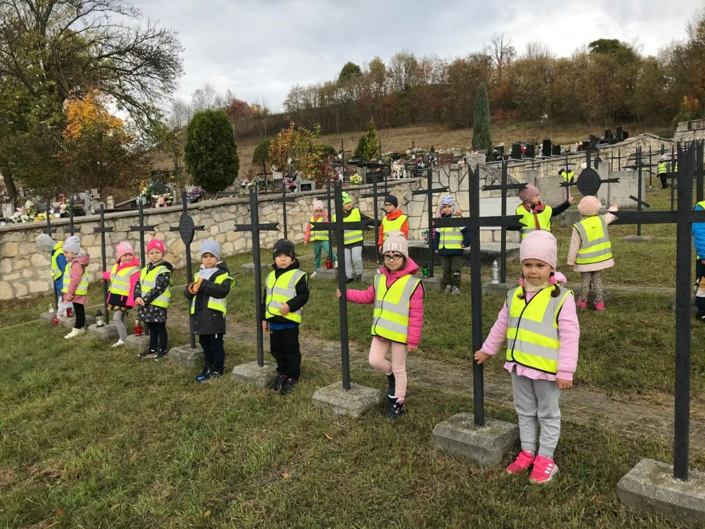 Dzieci stoją przy grobach żołnierzy. 