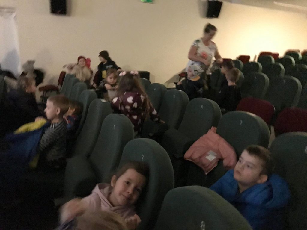Dzieci czekają na rozpoczęcie seansu w kinie.