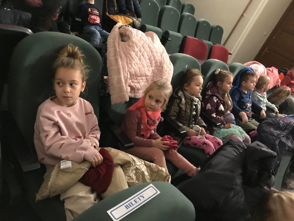 Dzieci czekają na rozpoczęcie seansu w kinie.