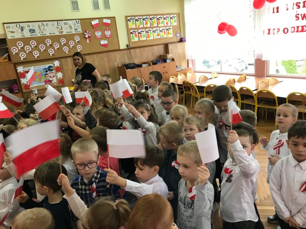 Dzieci machają biało czerwonymi flagami.