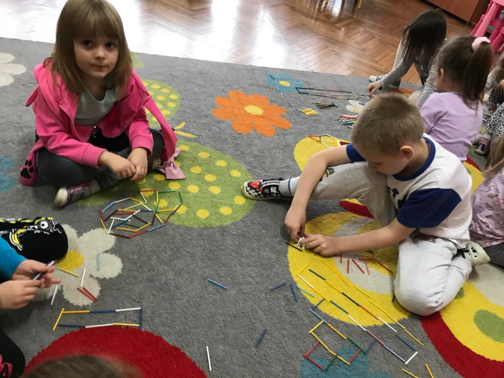 Dzieci układają obrazki z kolorowych patyczków.