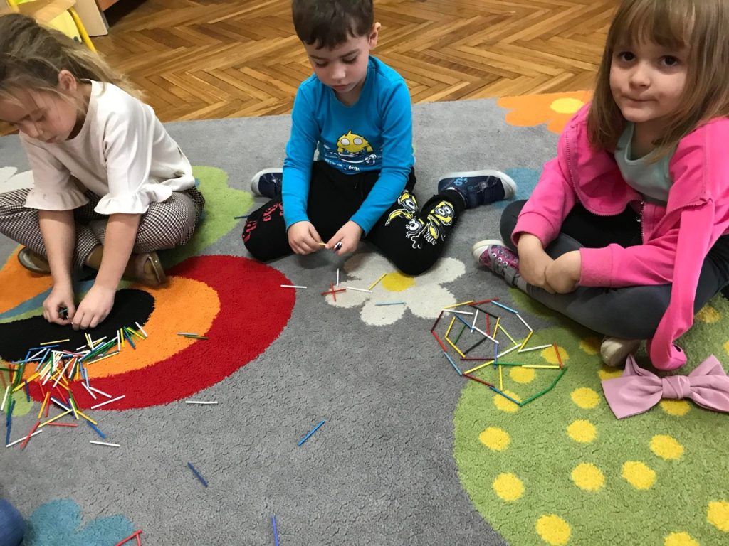 Dzieci układają obrazki z kolorowych patyczków.