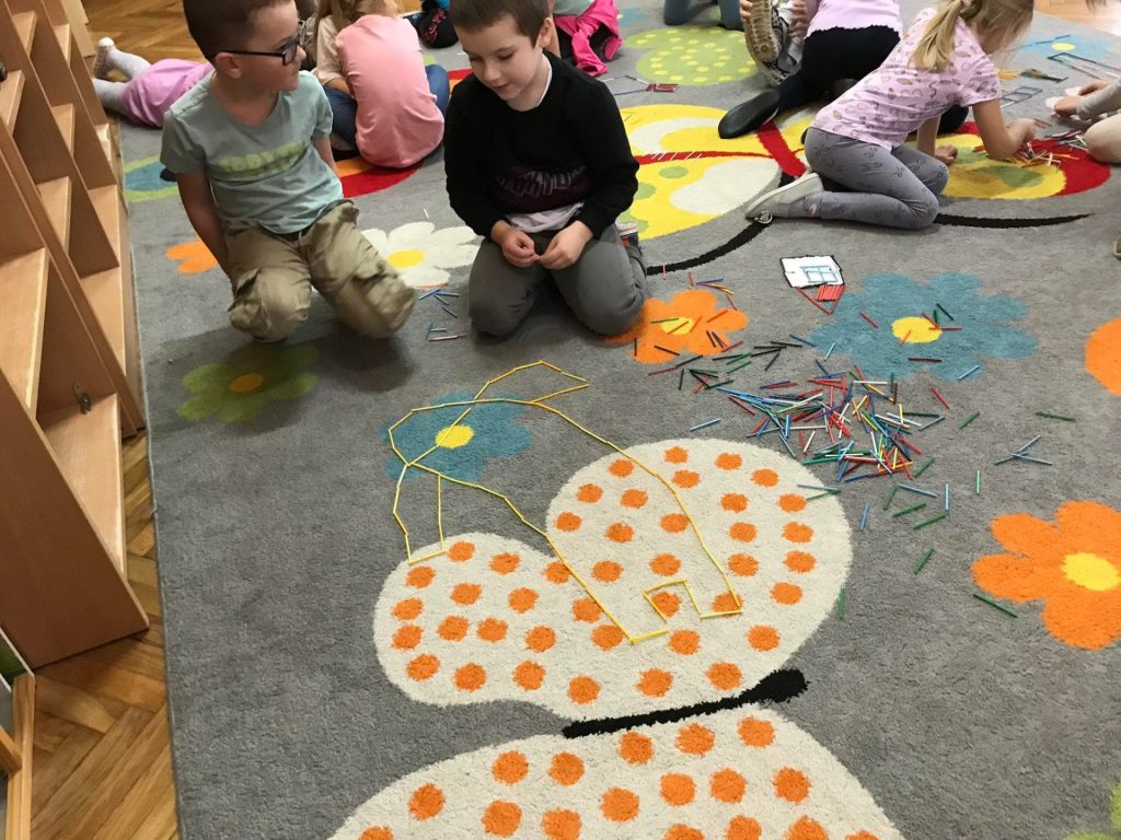 Chłopcy układają obrazki z kolorowych patyczków.