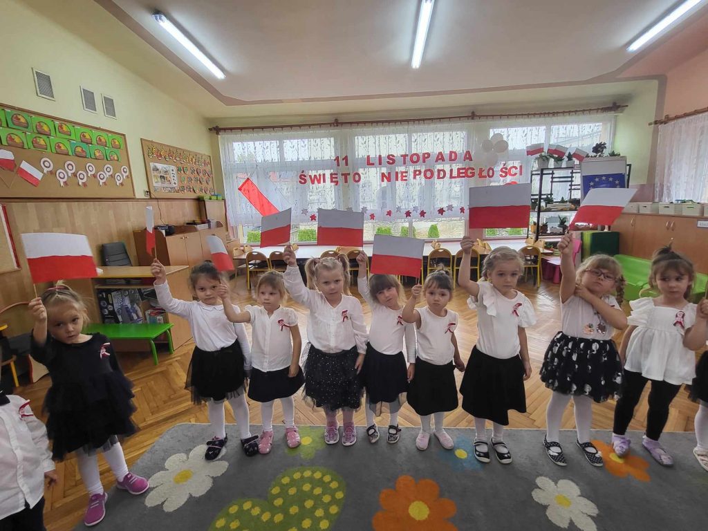 Przedszkolaki machają biało czerwonymi flagami