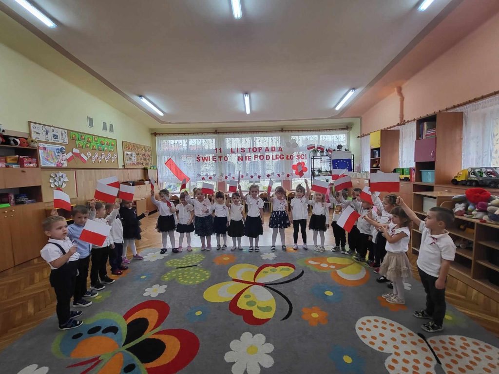 Przedszkolaki machają biało czerwonymi flagami
