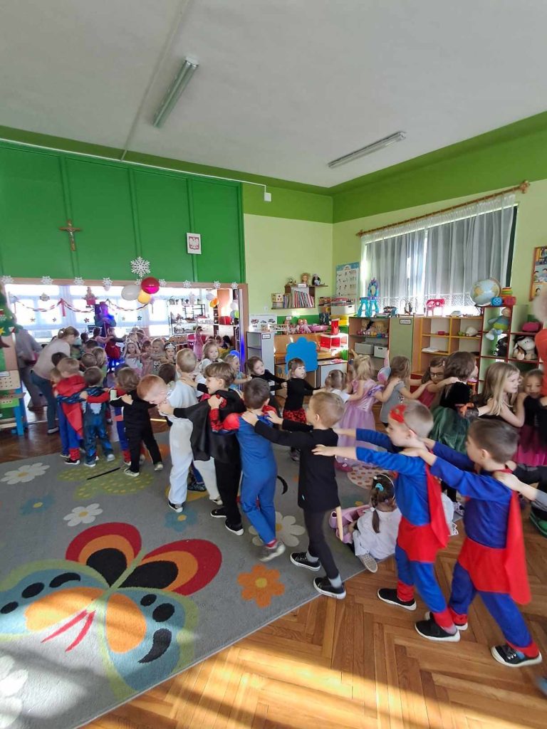 Dzieci w kolorowych przebraniach uczestniczą w zabawie karnawałowej