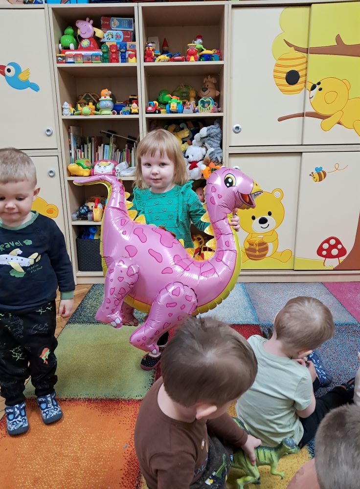Przedszkolaki pozują z dużym balonem w kształcie dinozaura