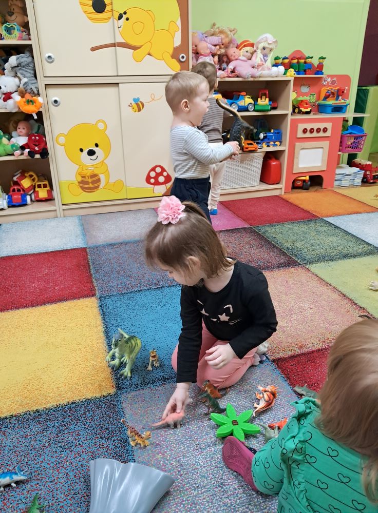 Dzieci z grupy Żabki bawią się zabawkami w kształcie dinozaurów, udają odgłosy dinozaurów