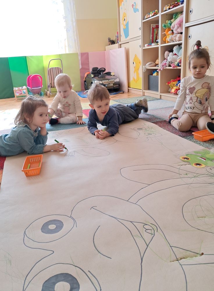 Dzieci z grupy Żabki z wielkim zaangażowaniem kolorowały na dużym kartonie Żabki