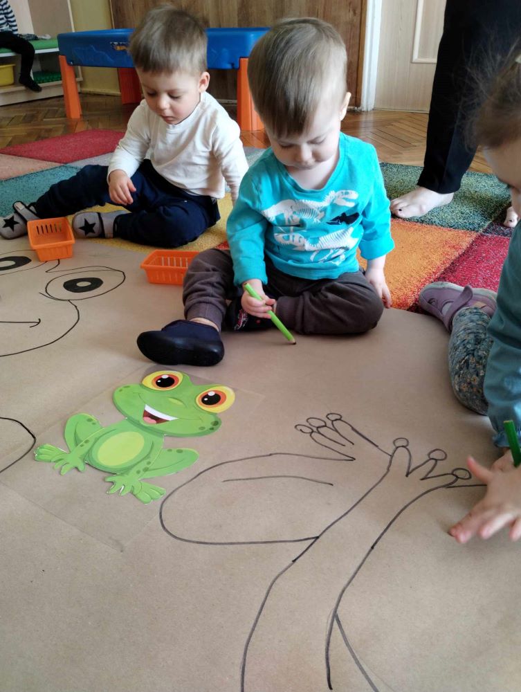 Dzieci z grupy Żabki z wielkim zaangażowaniem kolorowały na dużym kartonie Żabki