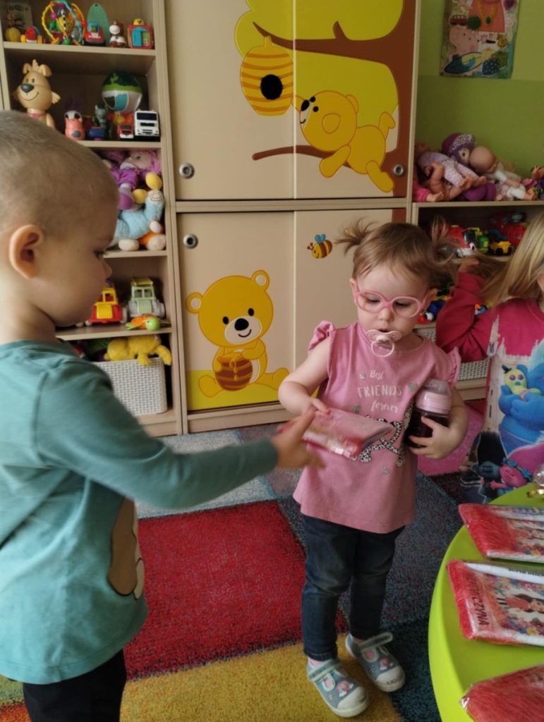 Chłopcy składają dziewczynką życzenia i dają małe upominki z okazji Dnia Kobiet