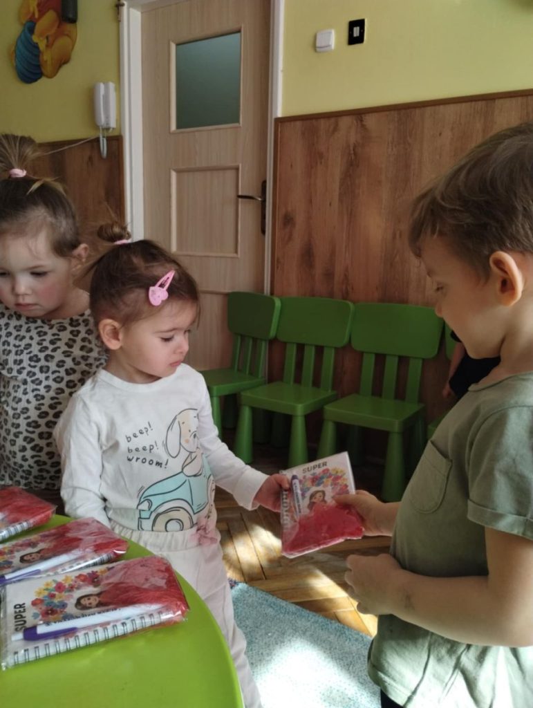 Chłopcy składają dziewczynką życzenia i dają małe upominki z okazji Dnia Kobiet