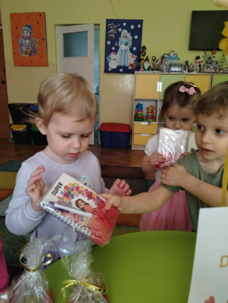 Chłopcy składają dziewczynką życzenia i dają małe upominki z okazji Dnia Kobiet