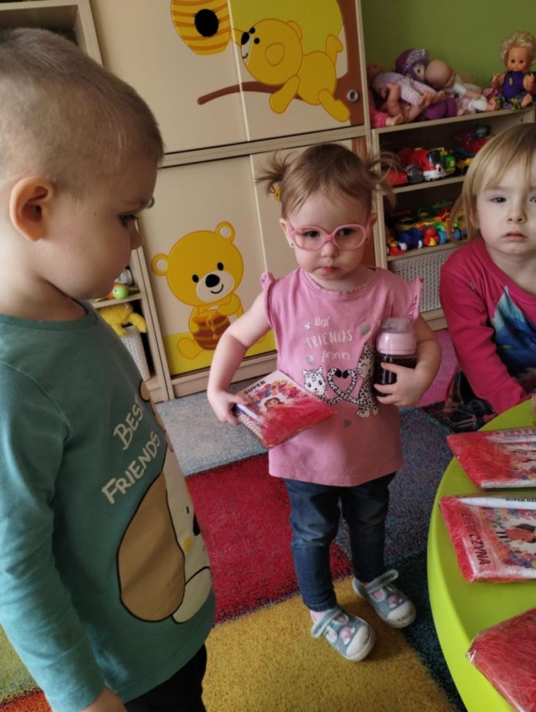 Chłopcy składają dziewczynką życzenia i dają małe upominki z okazji Dnia Kobiet