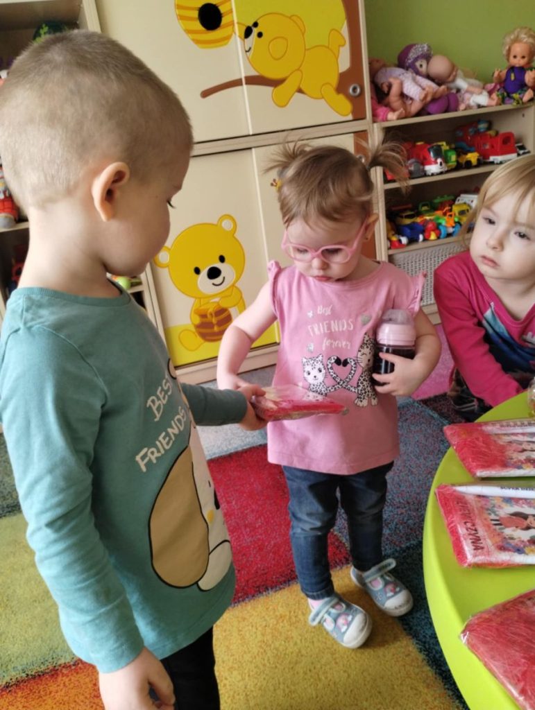 Chłopcy składają dziewczynką życzenia i dają małe upominki z okazji Dnia Kobiet