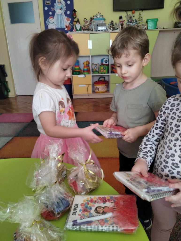 Chłopcy składają dziewczynką życzenia i dają małe upominki z okazji Dnia Kobiet