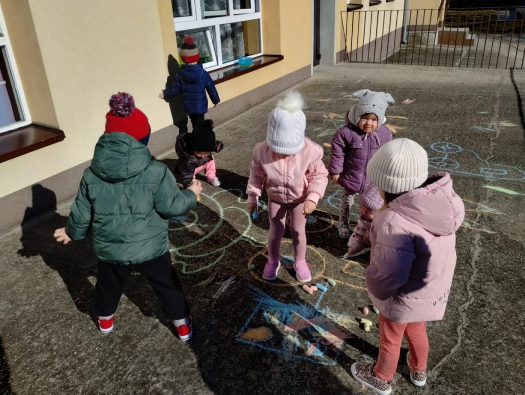 Dzieci rysują żabki kredą na tarasie