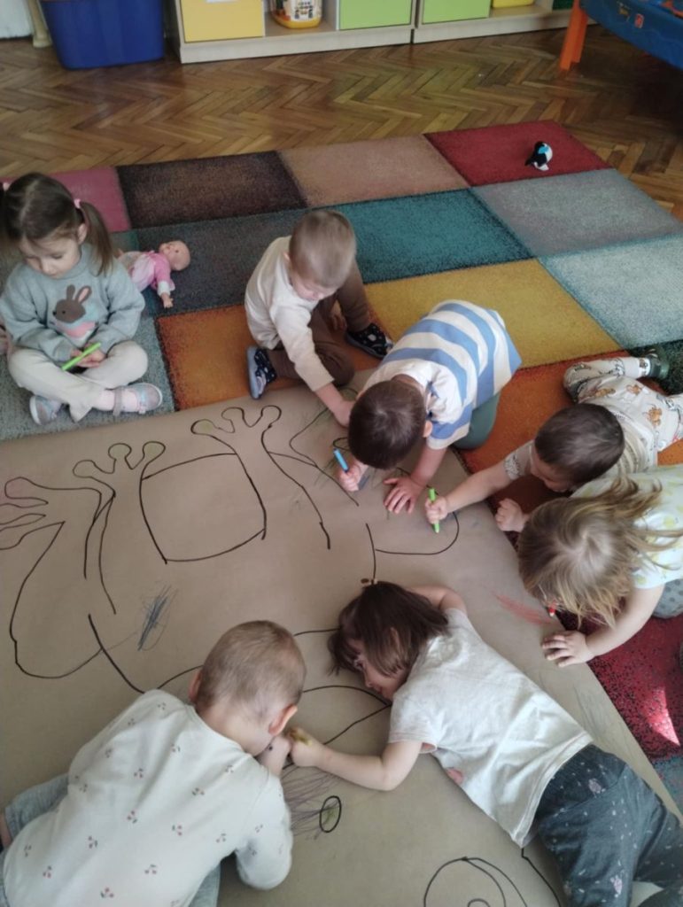 Dzieci z grupy Żabki kolorują postać żaby