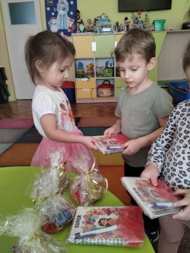 Chłopcy składają dziewczynką życzenia i dają małe upominki z okazji Dnia Kobiet