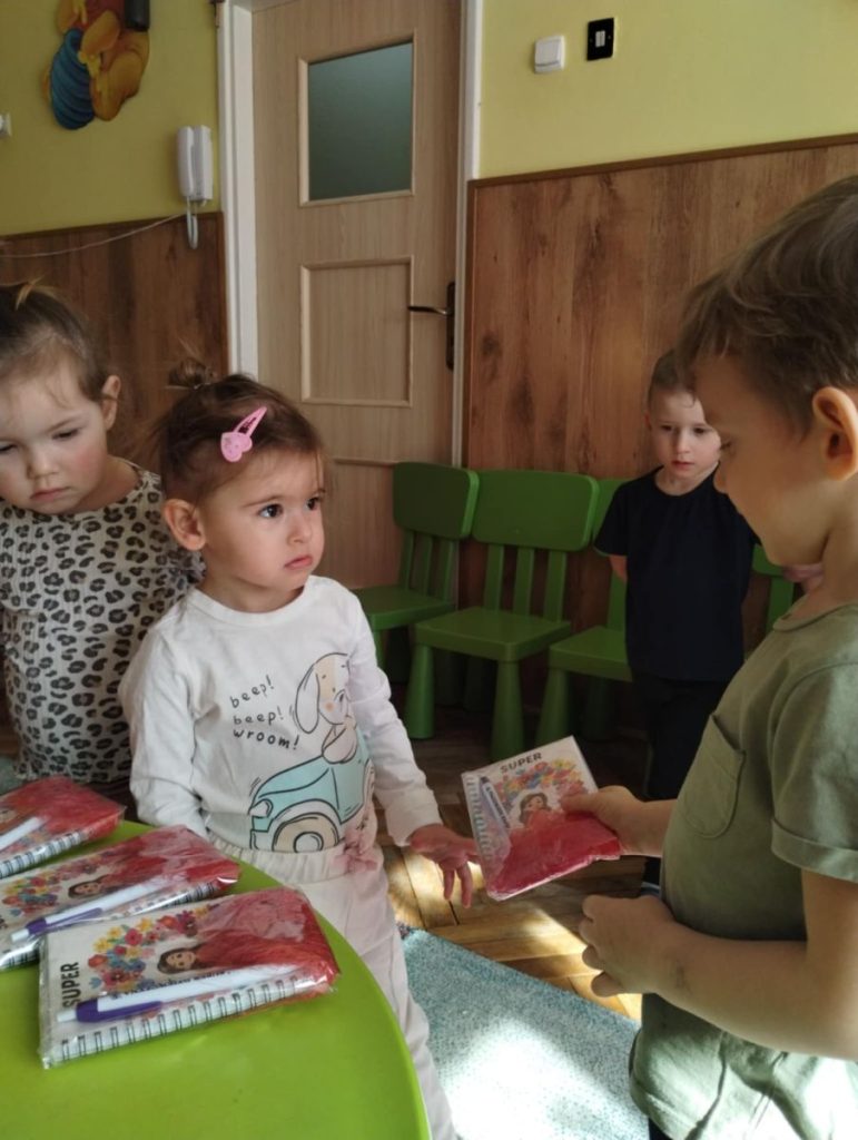 Chłopcy składają dziewczynką życzenia i dają małe upominki z okazji Dnia Kobiet