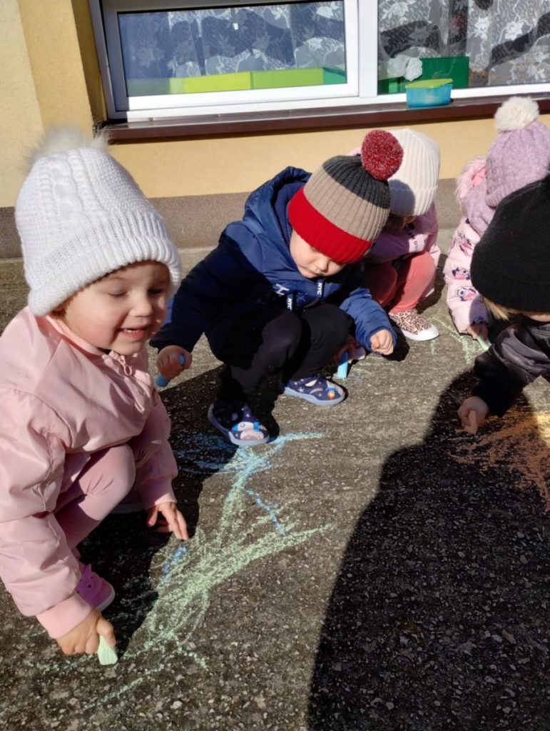 Dzieci rysują żabki kredą na tarasie