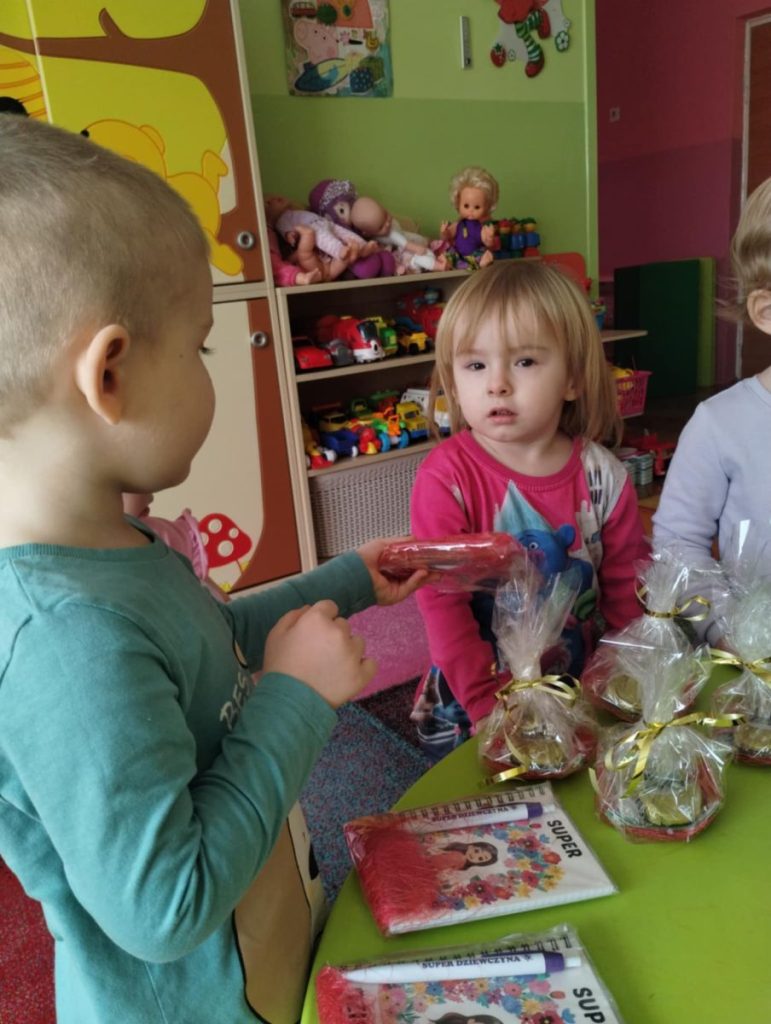 Chłopcy składają dziewczynką życzenia i dają małe upominki z okazji Dnia Kobiet