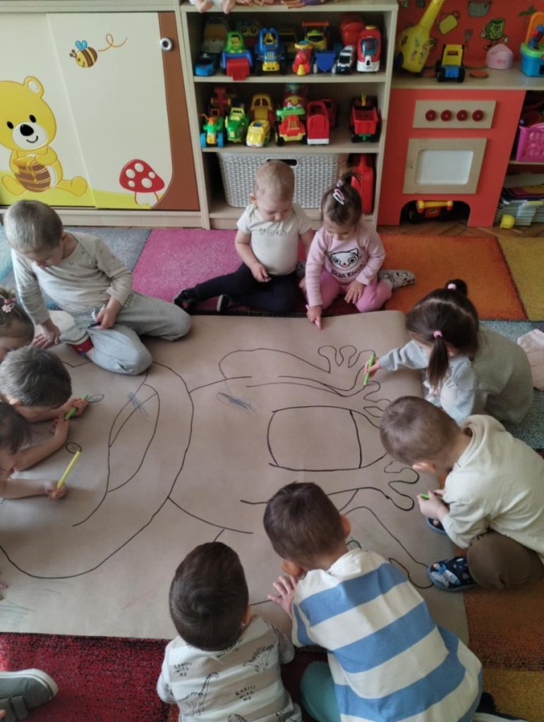 Dzieci z grupy Żabki kolorują postać żaby