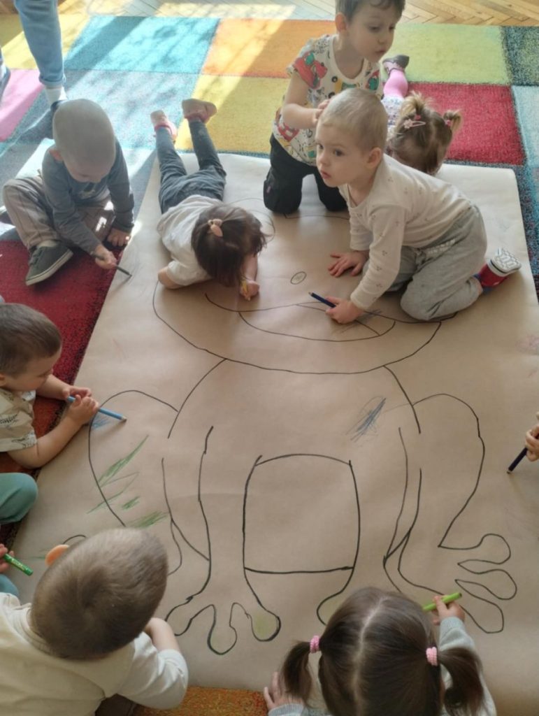 Dzieci z grupy Żabki kolorują postać żaby