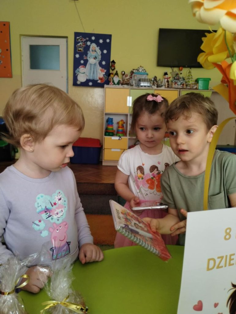 Chłopcy składają dziewczynką życzenia i dają małe upominki z okazji Dnia Kobiet