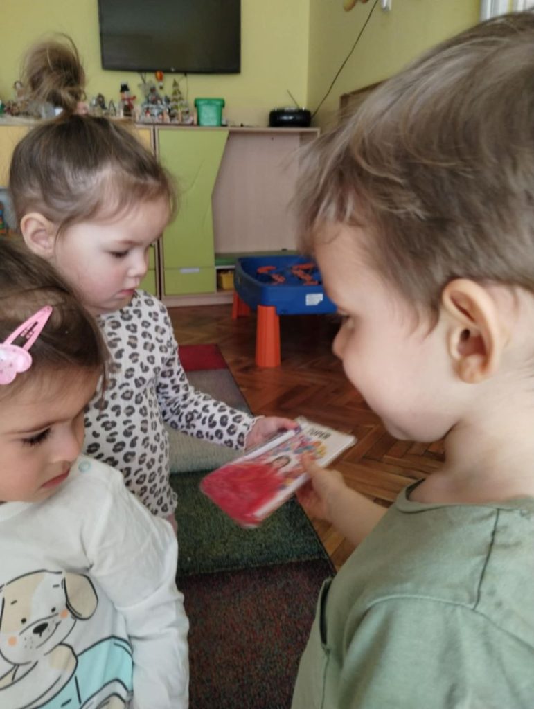 Chłopcy składają dziewczynką życzenia i dają małe upominki z okazji Dnia Kobiet