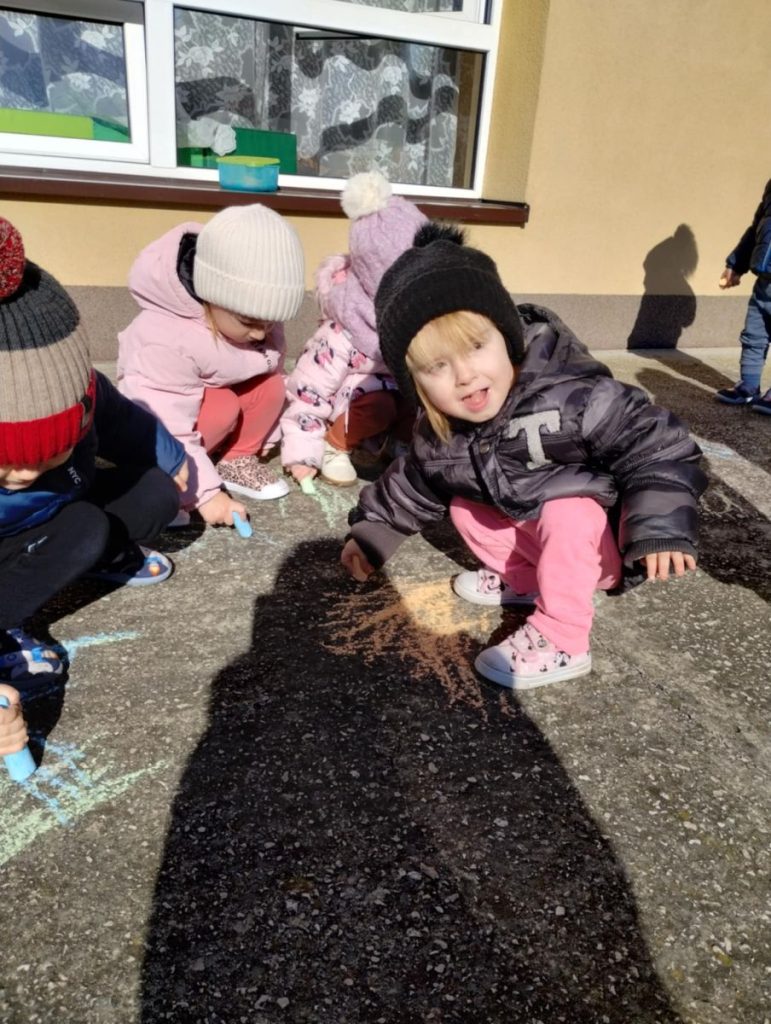 Dzieci rysują żabki kredą na tarasie