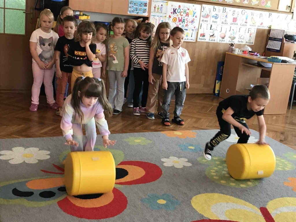 Dziewczynka toczy żółty walec.