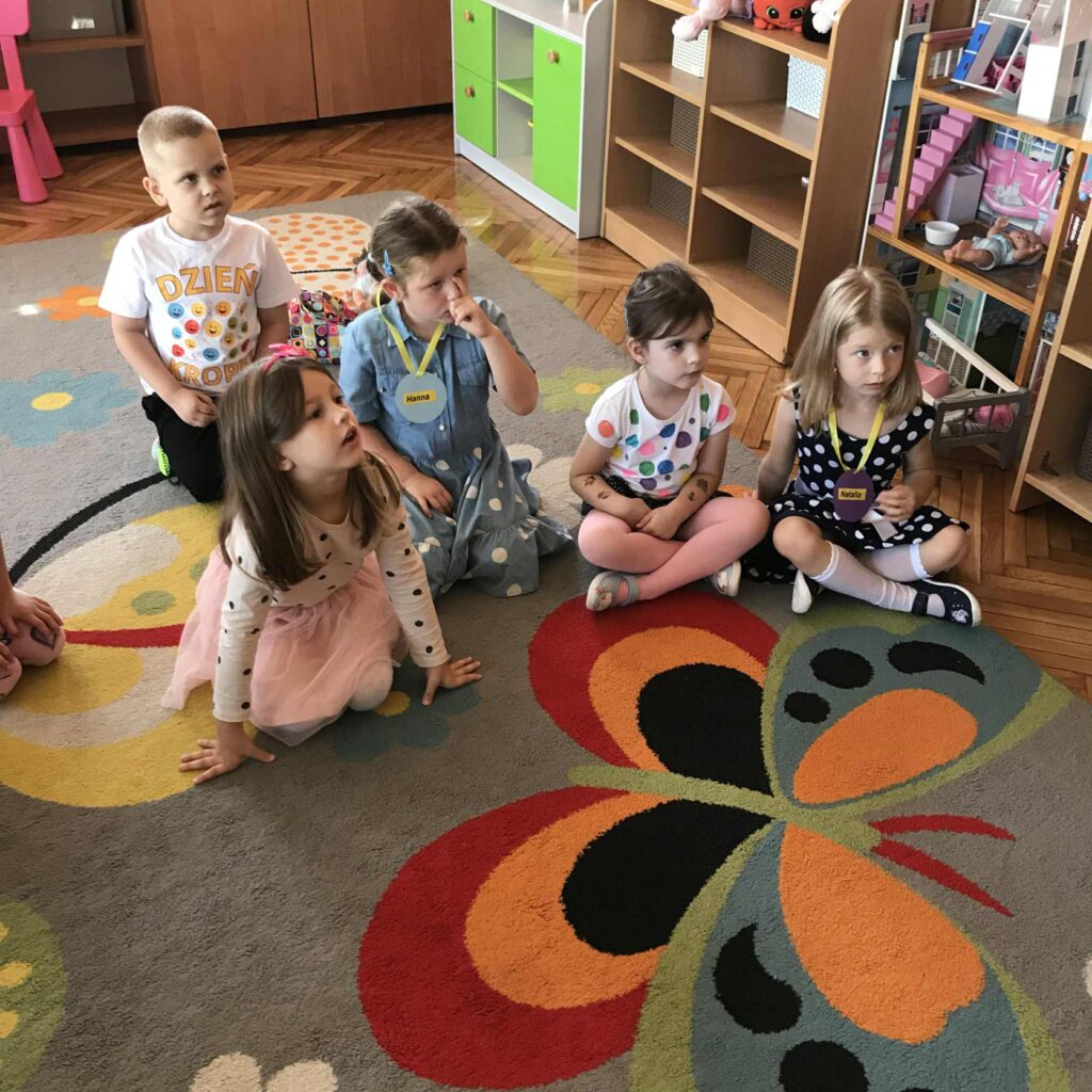 Dzieci siedzą na dywanie.
