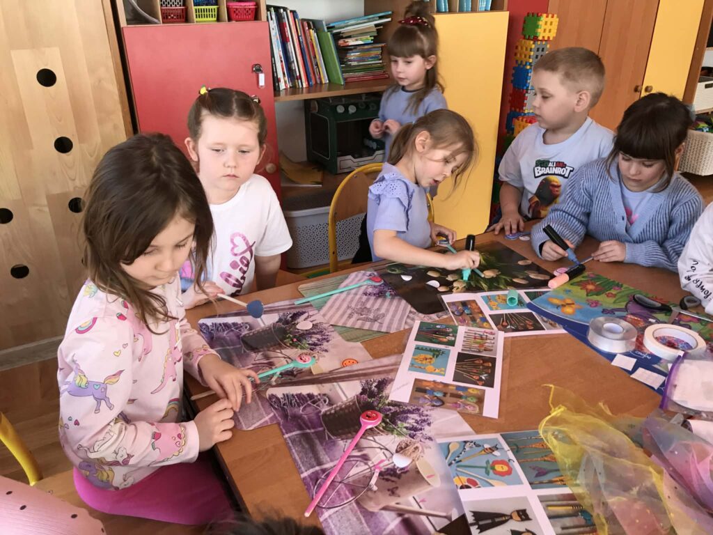 Dzieci tworzą przy stolikach własne kukiełki.