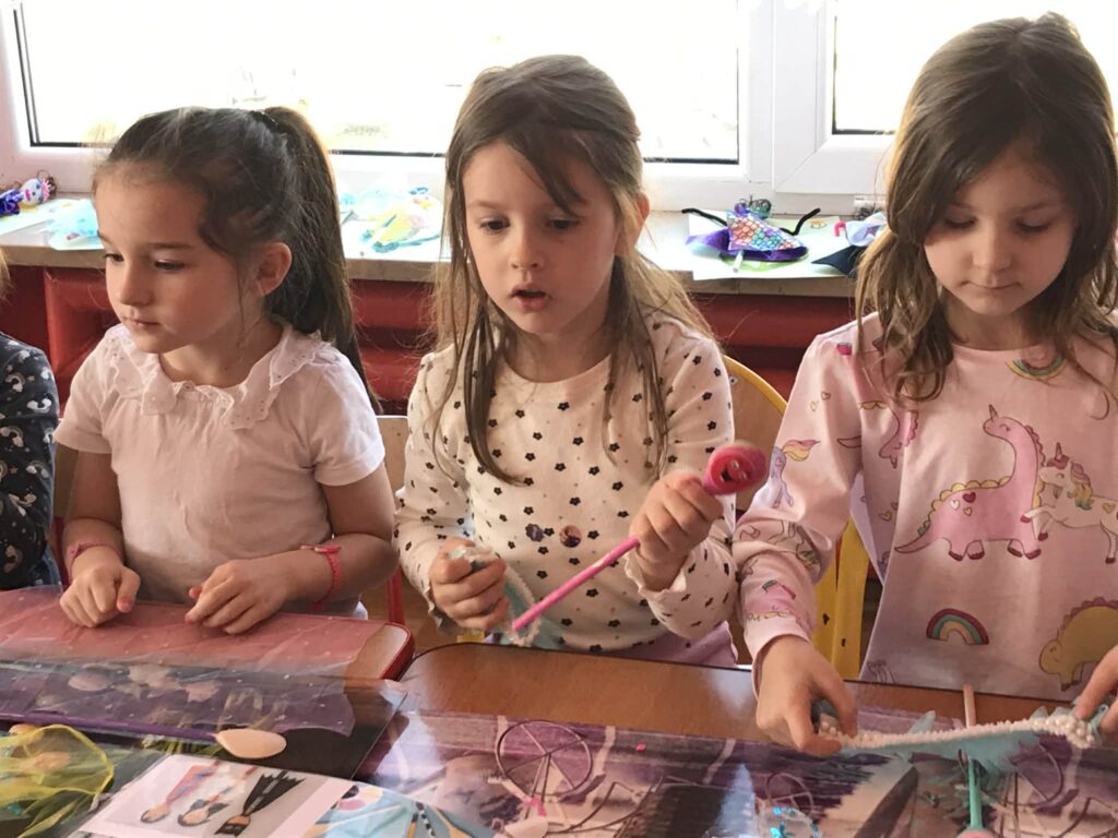 Dzieci tworzą przy stolikach własne kukiełki.